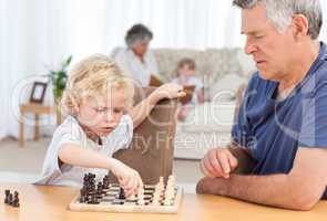 Young boy playing chess with his grandfather