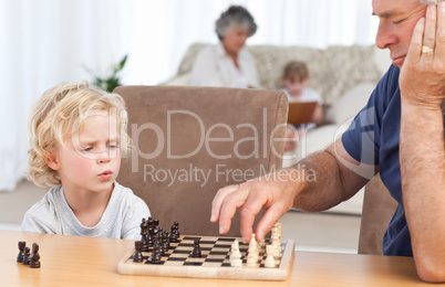 Young boy playing chess with his grandfather