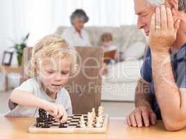 Young boy playing chess with his grandfather