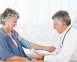 A senior doctor taking the blood pressure of his patient