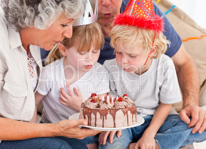 Children blowing on the birthday cake