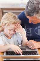 Lovely boy and his grandfather looking at their laptop