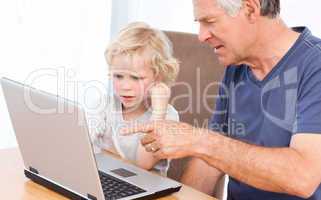 Lovely boy and his grandfather looking at their laptop