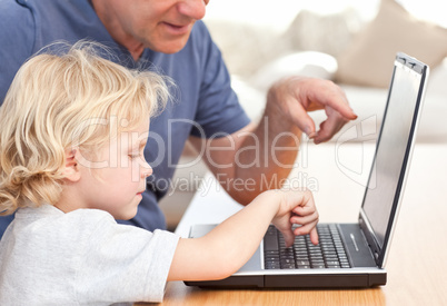 Lovely boy and his grandfather looking at their laptop