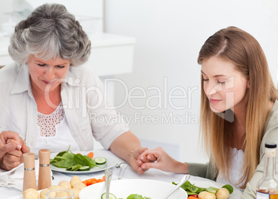 Woman and her mother praying at the table