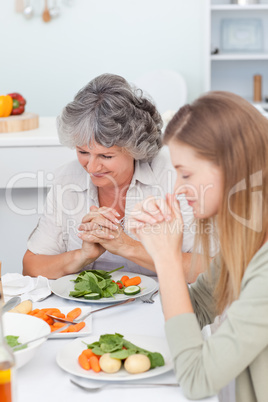 Woman and her mother praying at the table