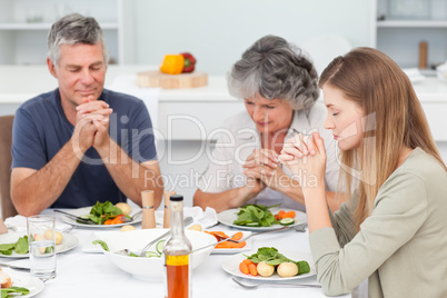 Adorable family praying at the table