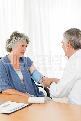 A senior doctor taking the blood pressure of his patient