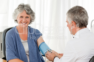 A senior doctor taking the blood pressure of his patient