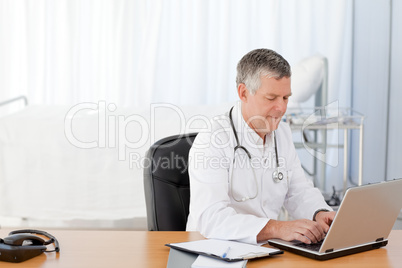 A senior doctor working on his laptop in his office