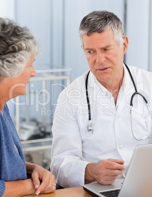 A senior doctor with his patient looking at the laptop