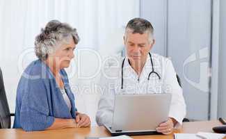 A senior doctor with his patient looking at the laptop
