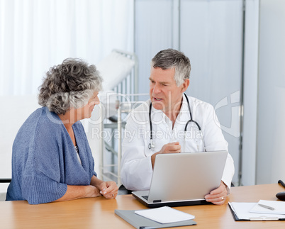 A senior doctor with his patient looking at the laptop