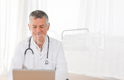 A senior doctor working on his laptop in his office