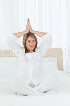 Senior practicing yoga on her bed