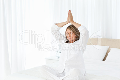 Senior practicing yoga on her bed