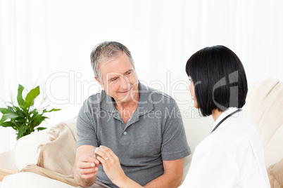 Nurse showing pills to her mature patient