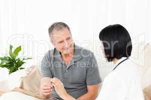 Nurse showing pills to her mature patient
