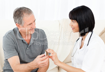 Nurse showing pills to her mature patient