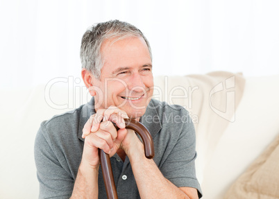 Mature man with his walking stick on his bed at home