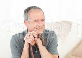 Mature man with his walking stick on his bed at home