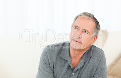 Mature man thoughtful with his walking stick on his bed