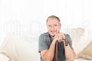 Mature man with his walking stick on his bed