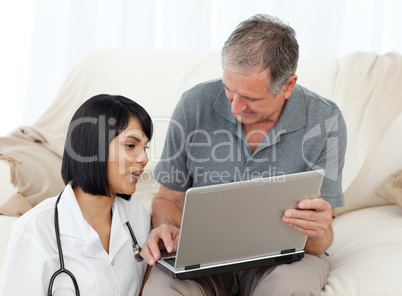 Mature man with his nurse looking at the laptop at home