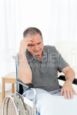 Senior in his wheelchair having a headache