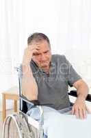 Senior in his wheelchair having a headache