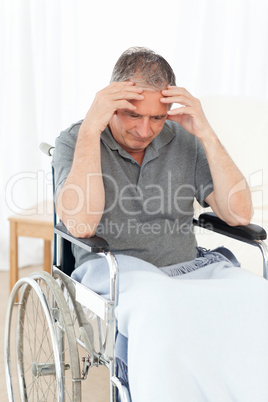 Senior in his wheelchair having a headache