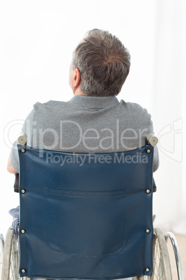 Mature man in his wheelchair with his back to the camera