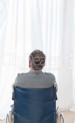 Mature man in his wheelchair with his back to the camera