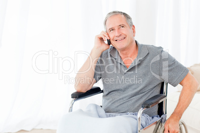 Senior in his wheelchair phoning Senior in his wheelchair phoning