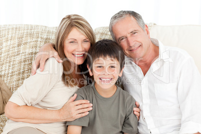 A little boy with his grandparents looking at the camera