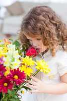 A little girl smelling  flowers