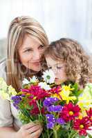 Little girl smelling flowers while her grandmother is smilling