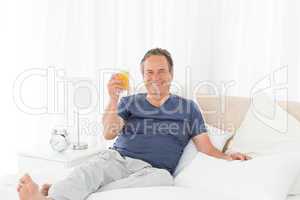 Retired man looking at the camera while he is drinking oranje ju