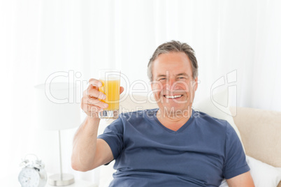 Retired man looking at the camera while he is drinking oranje ju