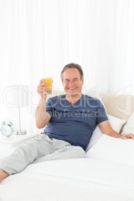 Retired man looking at the camera while he is drinking oranje ju