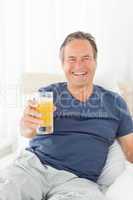 Retired man looking at the camera while he is drinking oranje ju