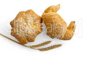 Croissant and bread roll with stems of wheat