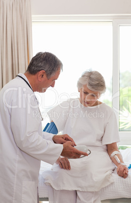 Mature doctor taking the blood pressure of his patient