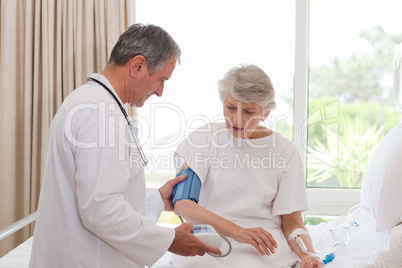 Mature doctor taking the blood pressure of his patient