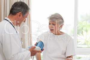 Mature doctor taking the blood pressure of his patient