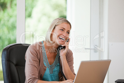 Woman working on her computer while she is phoning