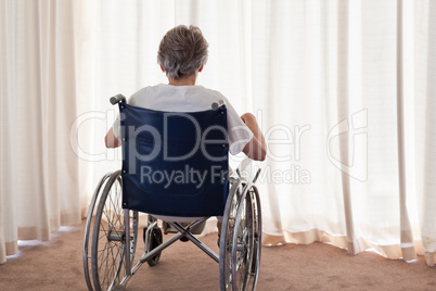 Mature woman in her wheelchair with her back to the camera at ho