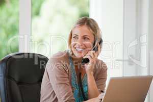 Woman working on her computer while she is phoning