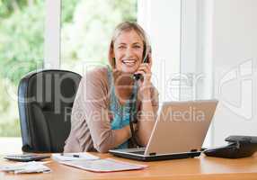 Woman working on her computer while she is phoning