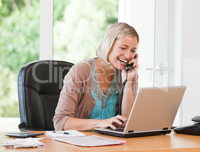 Woman working on her computer while she is phoning